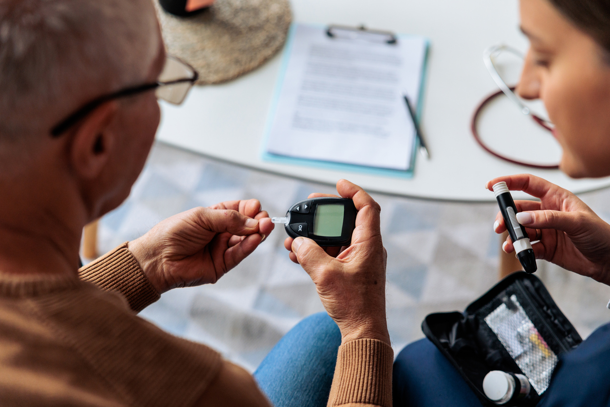 Home Nurse Assisting Senior Man with Blood Sugar Test